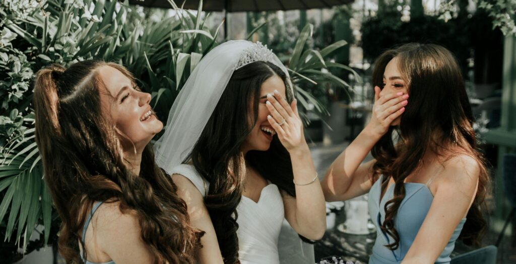 A maid of honour and the bride laugh.